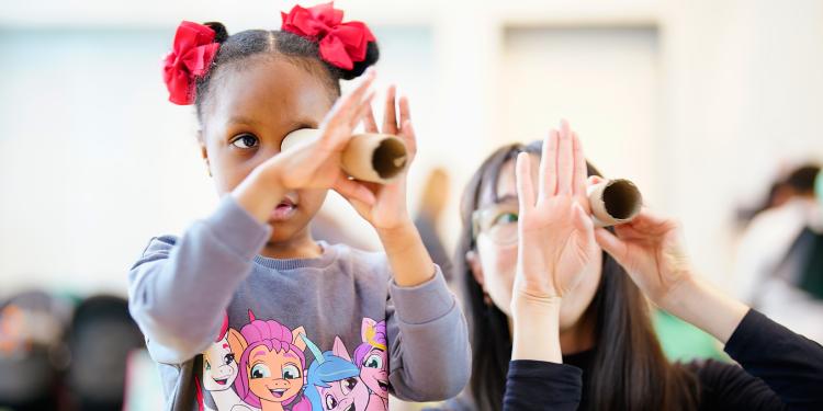 A child and an adult look through cardboard tubes together