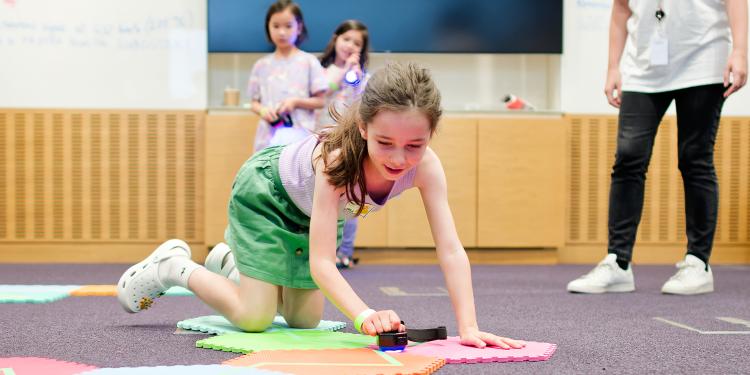 A child builds a cell on the floor with flat blocks