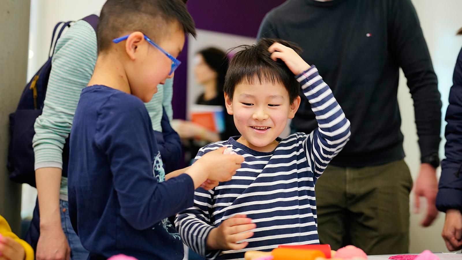 Two children look delighted while playing with a science activity
