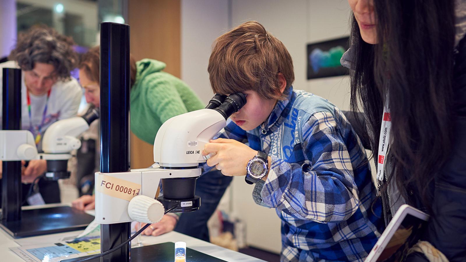 A young person looks through a microscope