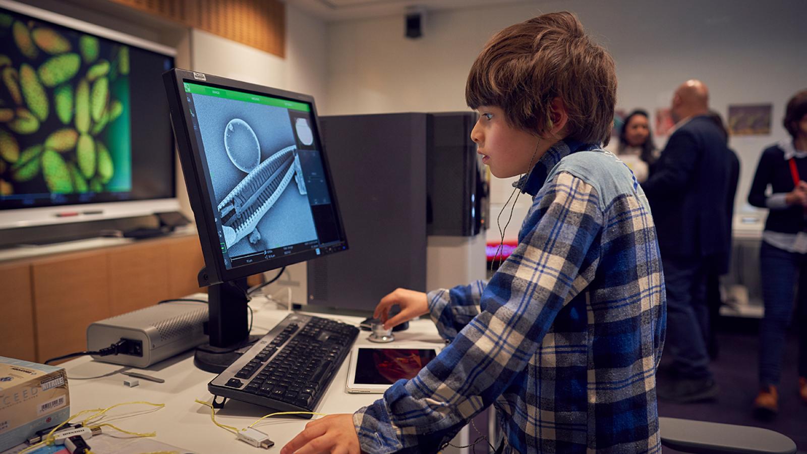 A young person looks at a screen showing something magnified by an electron microscope