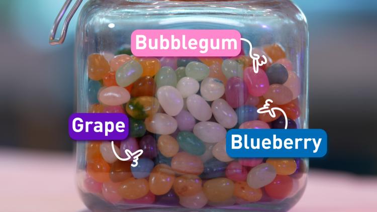 A glass jar full of colourful jellybean sweets. 3 sweets are labelled 'Bubblegum', 'Blueberry' and 'Grape'.
