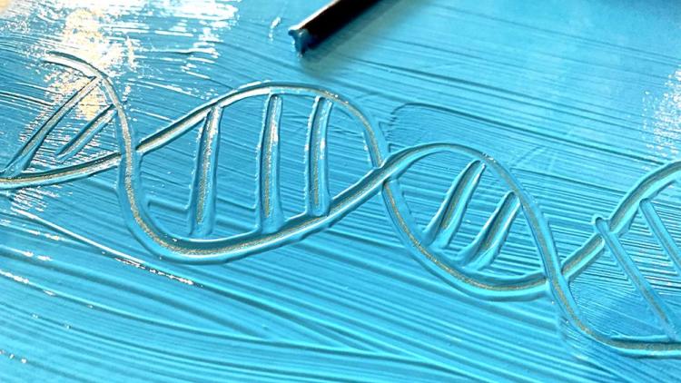 A piece of paper covered in blue paint with the design of a DNA structure scratched into it.