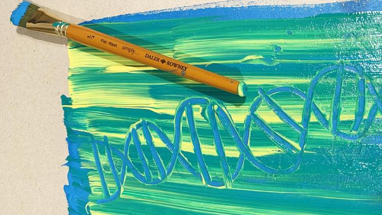 A piece of paper covered in stripes of yellow, green and blue paint with a DNA design drawn into it.