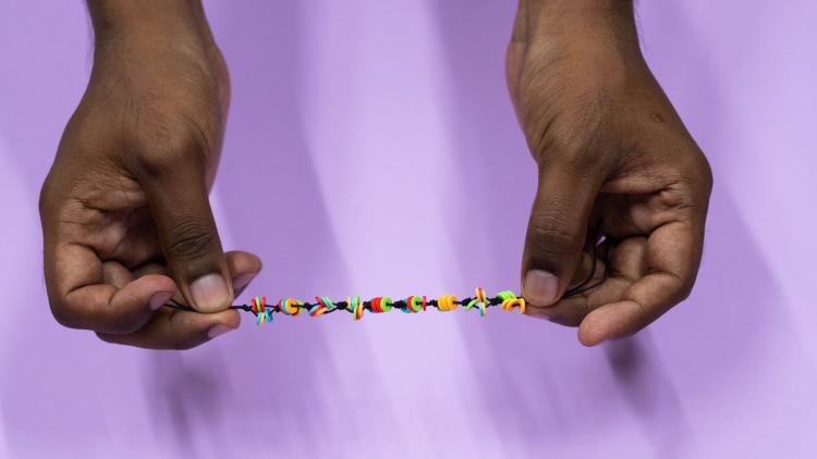 Two hands hold a bracelet